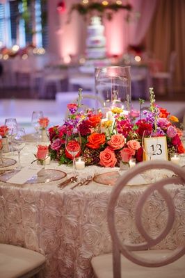 the table is set with flowers and candles for an elegant wedding reception in pinks, oranges and yellows