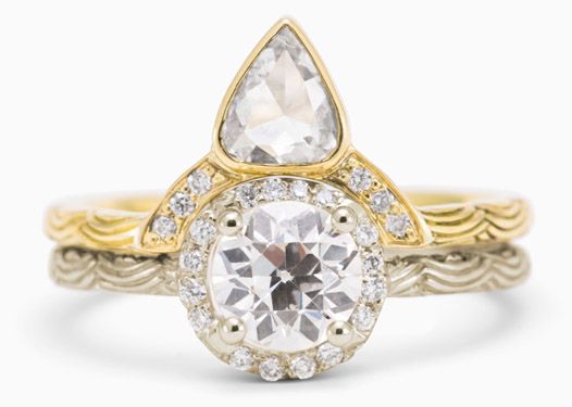 an engagement ring with a pear shaped diamond in the center and two tone gold band