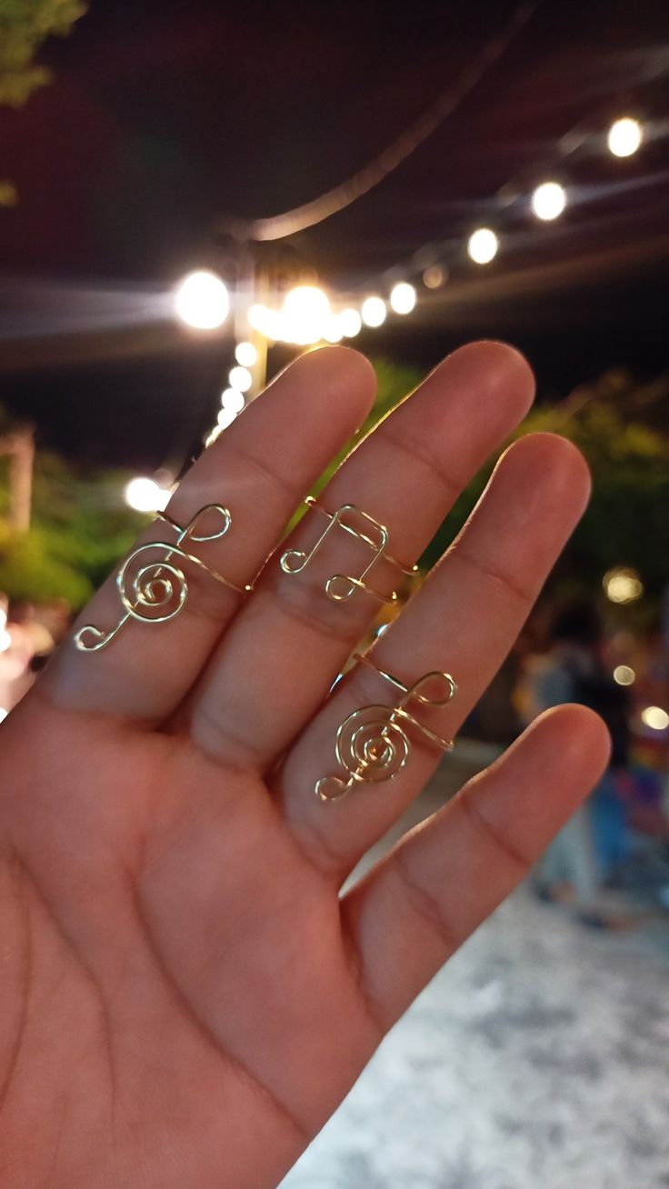 a person's hand holding three rings in the middle of their palm, with lights behind them