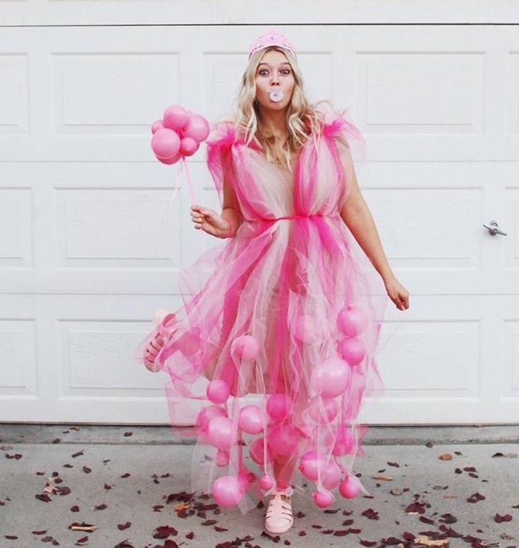 a woman in a pink dress with balloons on her head and nose, standing next to a garage door