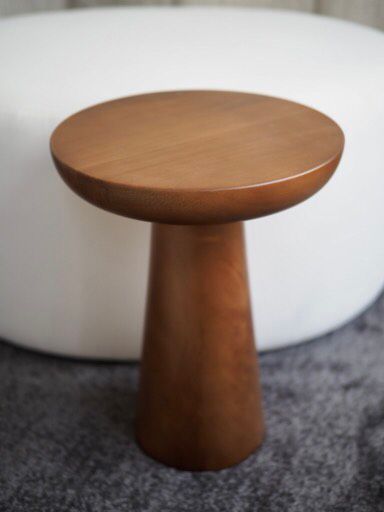 a wooden table sitting on top of a carpeted floor next to a white couch