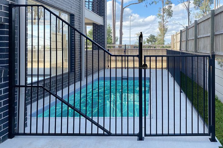 an empty swimming pool is seen through the gated entrance to a building with palm trees in the background