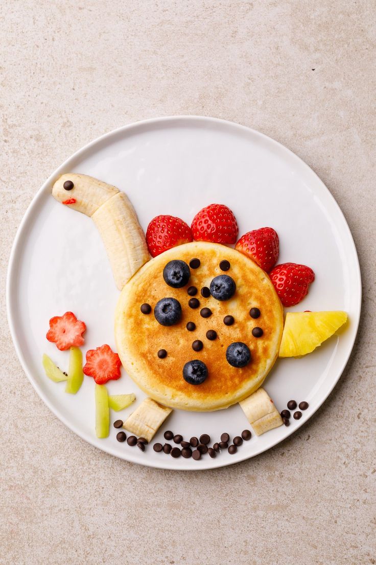 a white plate topped with pancakes and fruit on top of it next to a banana