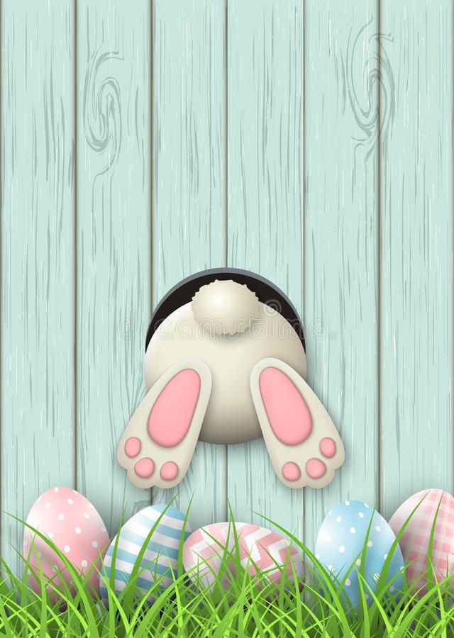 an easter bunny with ears peeking out from behind some eggs in the grass on a wooden background