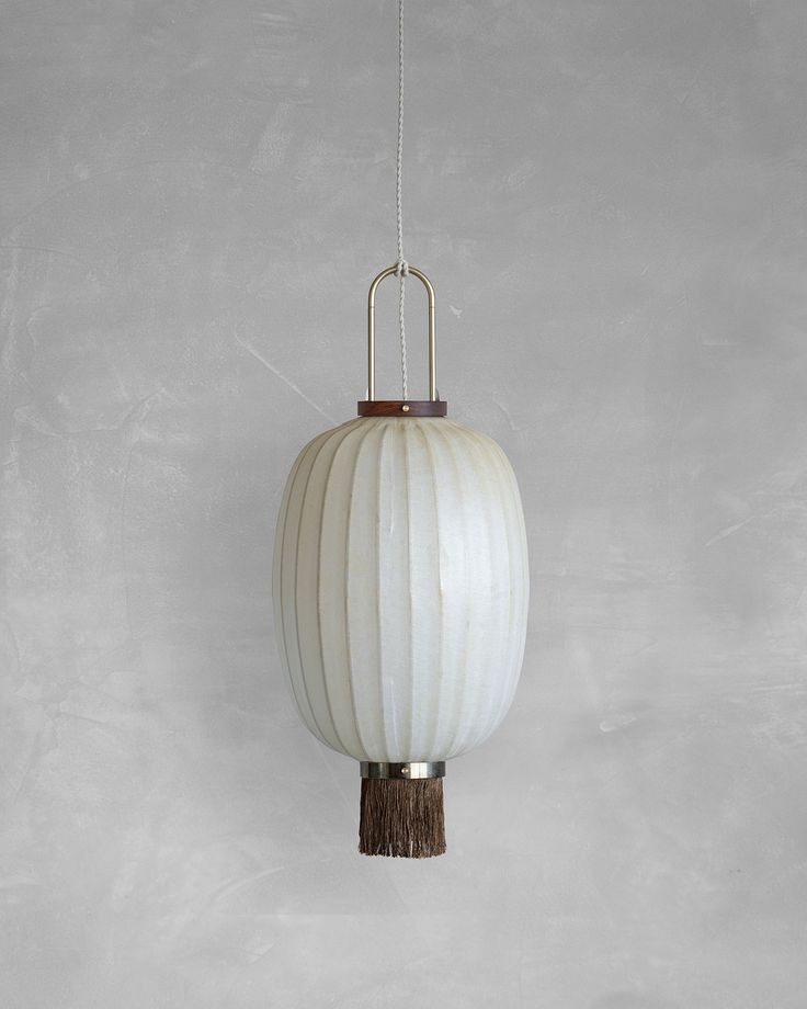 a white light hanging from a metal chain on a gray wall with a wooden handle