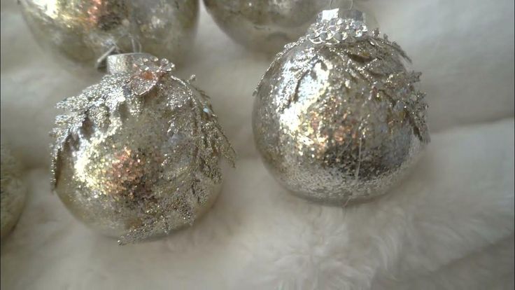 four shiny silver christmas ornaments on white fur