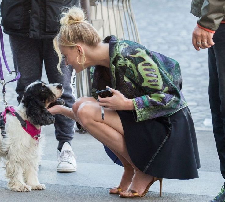 a woman kneeling down petting a dog on the street