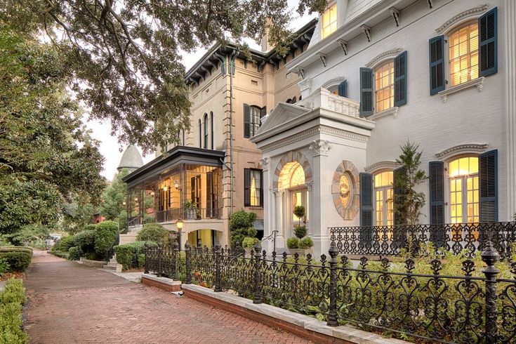 a large white house with many windows and iron fenced in walkway leading up to it