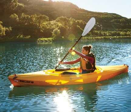 a woman in a yellow kayak paddles through the water on a sunny day