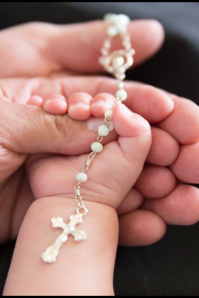 a person holding a baby's hand with a rosary on it