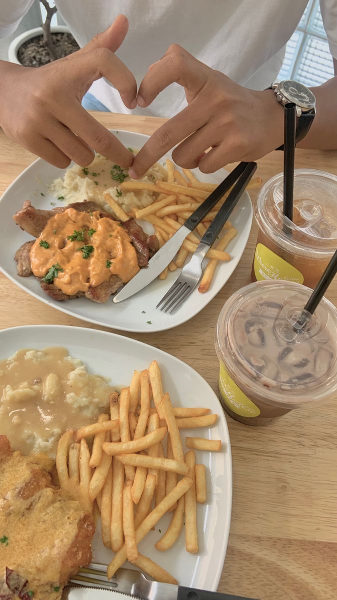 two white plates topped with food next to fries and gravy on top of a wooden table