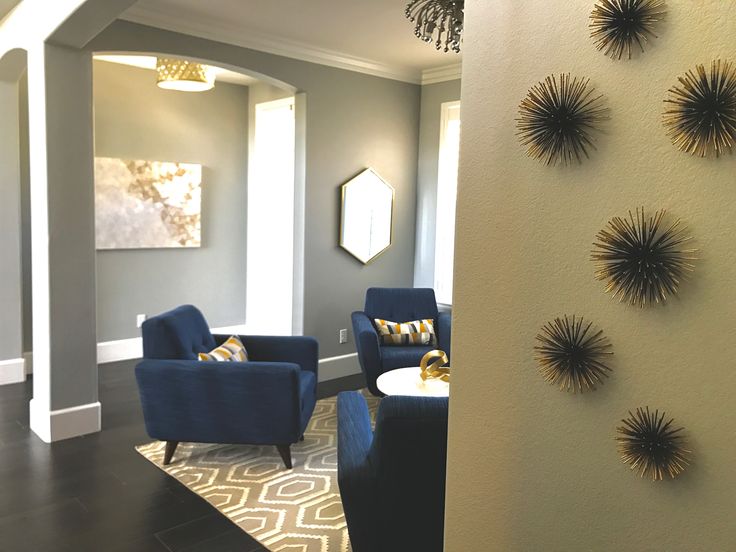 a living room filled with blue chairs next to a wall mounted art on the wall