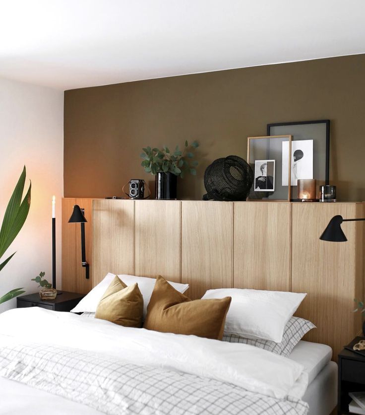 a bed with white sheets and pillows next to a wooden headboard in a bedroom