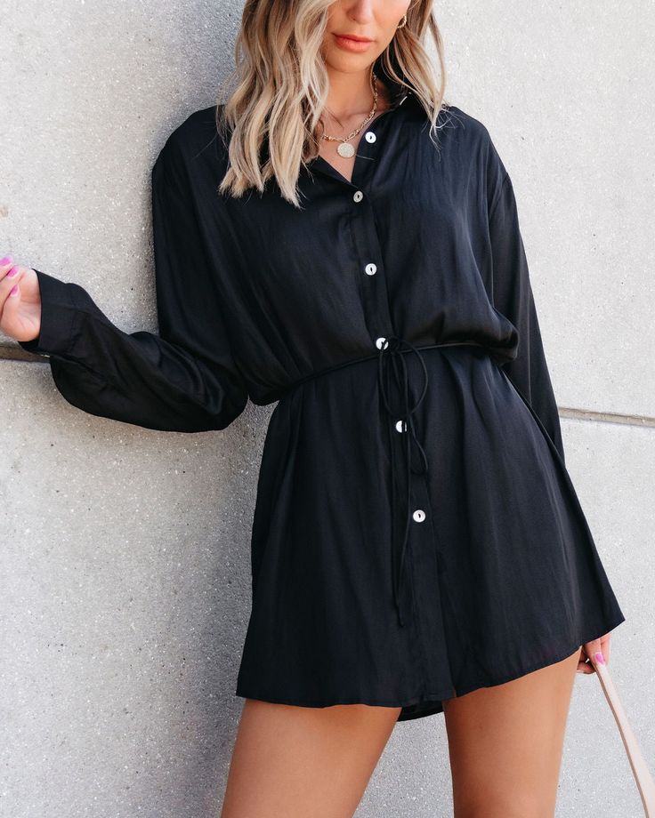 Details Our Black Silky Button Down Romper is luxuriously soft & elegant making it the perfect fall staple piece! Features include long sleeves with button cuffs, a collared neck, functional buttons, side slits, and lined shorts. Style with knee high boots, elevated gold jewelry, and a trendy crossbody to complete the look. Soft, silky feel Long sleeve with button cuffs Dropped shoulder Collared neckline Button down front Side slits Back yoke Lined shorts Mini length Relaxed fit 100% Polyester Hand wash cold Line dry Color: Black Colors may vary from different viewing devices. Size and Fit S (2-4) M (6-8) L (10-12) Length measurements from shoulder to hem S: 30.5" M: 31" L: 31.5" Model Info Model is 5’6 and is wearing a size small. Long Sleeve Shirt Dress For Date Night, Solid Long Sleeve Shirt Dress With Buttons, Chic Long Sleeve Solid Color Shirt Dress, Long Sleeve Shirt Dress With Button Cuffs For Fall, Spring Long Sleeve Shirt Dress With Buttoned Pockets, Chic Long Sleeve Shirt Dress With Button Closure, Chic Shirt Dress With Button Cuffs For Day Out, Fall Solid Shirt Dress With Buttons, Fall Solid Color Shirt Dress With Buttons