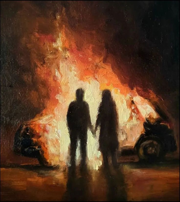 two people standing in front of a fire with a car on the road behind them