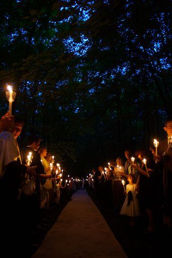 many people are holding candles in their hands and walking down a path at night time