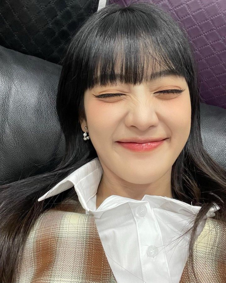 a woman with long black hair wearing a white shirt and earrings smiling at the camera