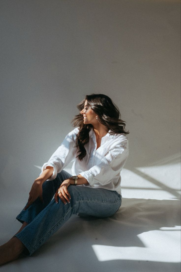 a woman is sitting on the floor with her legs crossed and looking off to the side