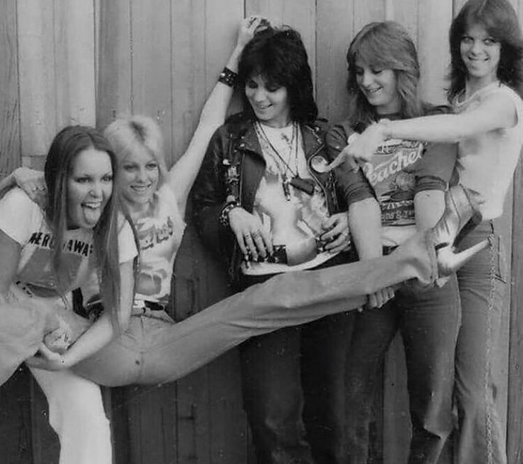 four young women are posing with their legs stretched out in front of a wooden wall