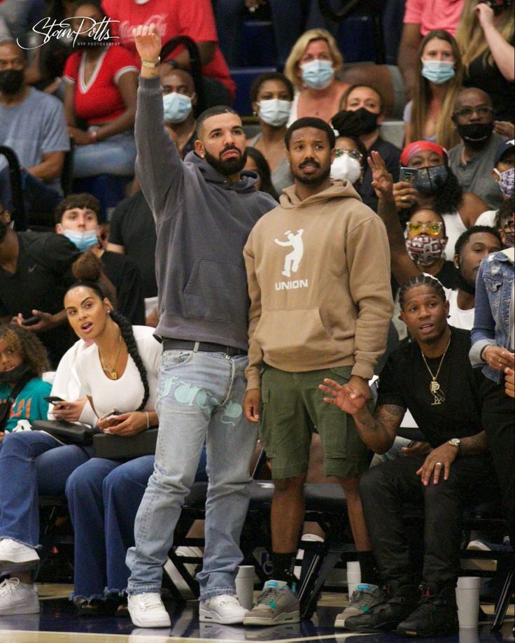 a man standing in front of a crowd wearing a face mask and raising his hand up