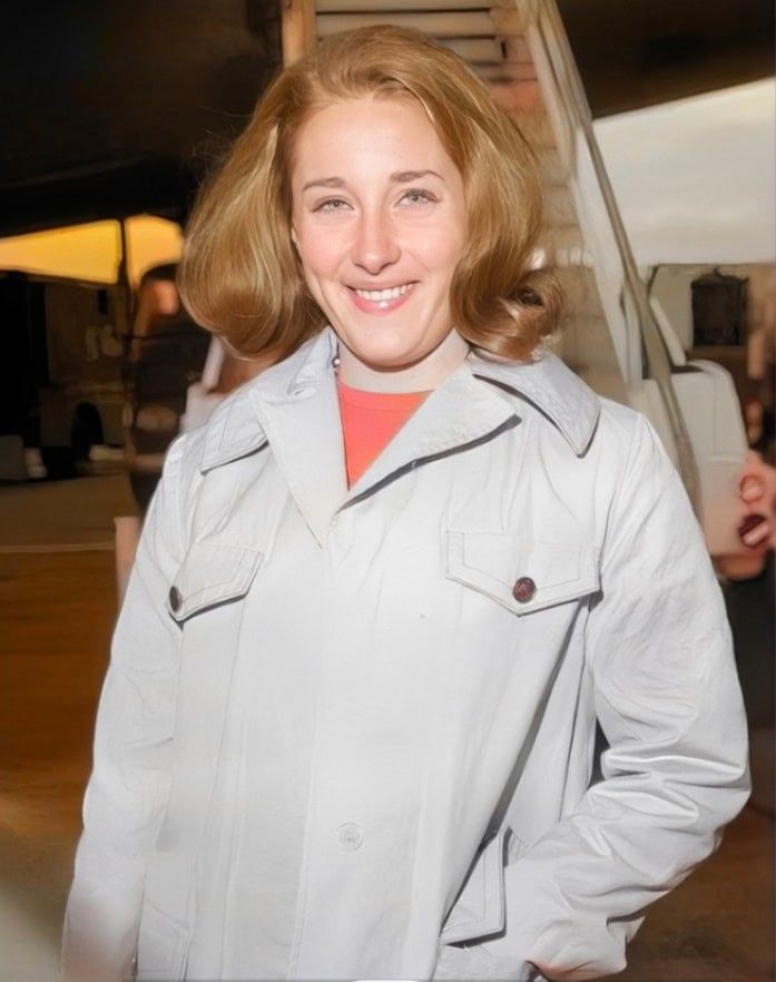 a woman standing in front of an airplane with her hands on her hips and smiling