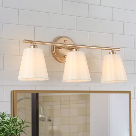 three light bathroom fixture with white shades on the wall and mirror in front of it