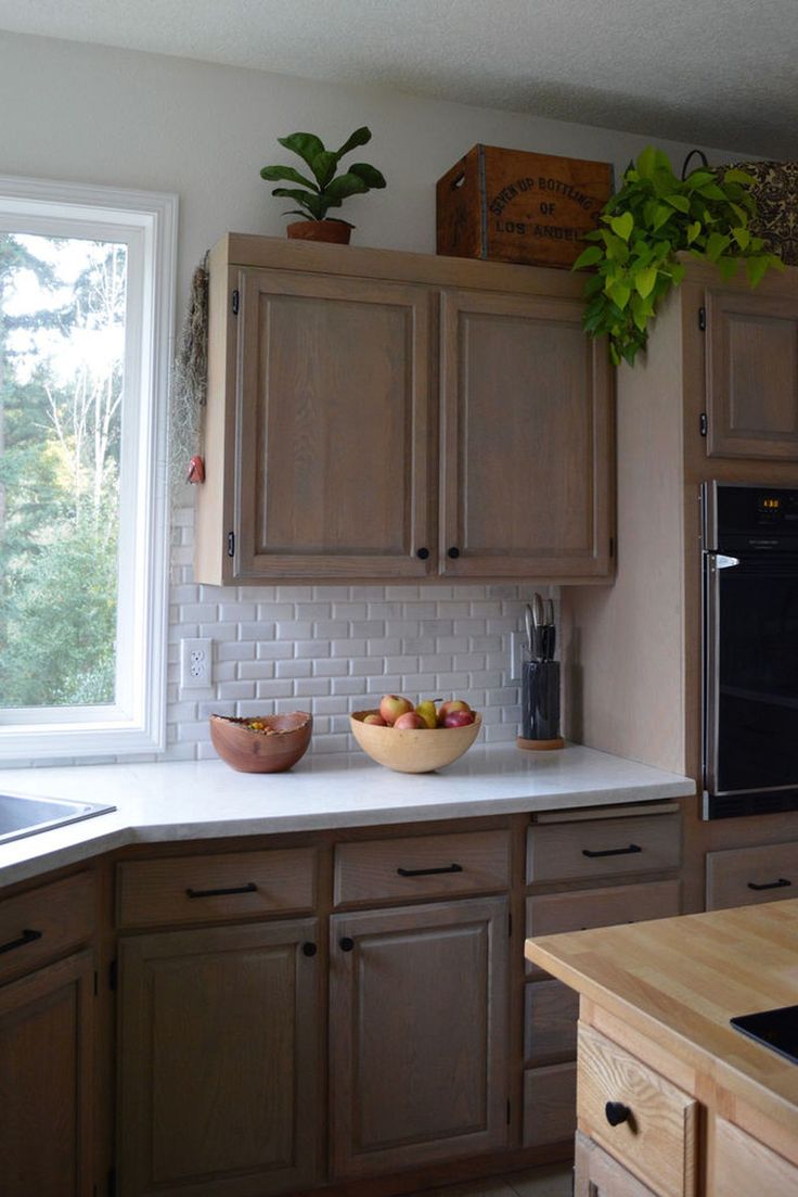 a bowl of fruit is sitting on the counter top in a kitchen with wooden cabinets