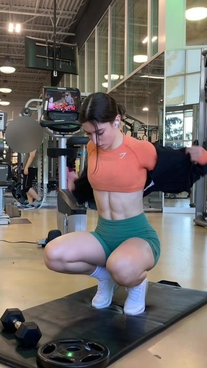 a woman squatting on a mat in a gym