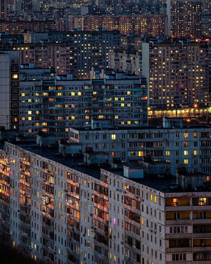 the city is lit up at night with many buildings in the foreground and lights on