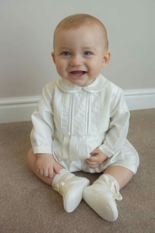 a baby sitting on the floor wearing white shoes