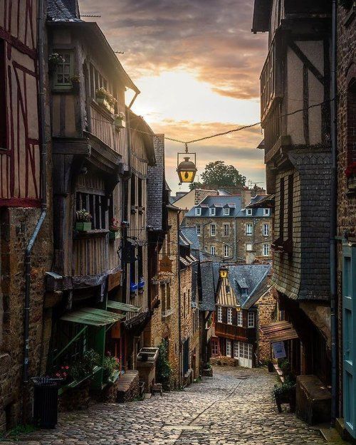 an alleyway with cobblestone streets and old buildings in the background at sunset