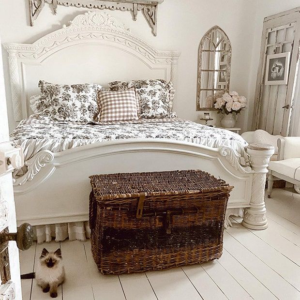 a bedroom with white walls and flooring has a basket on the floor next to the bed