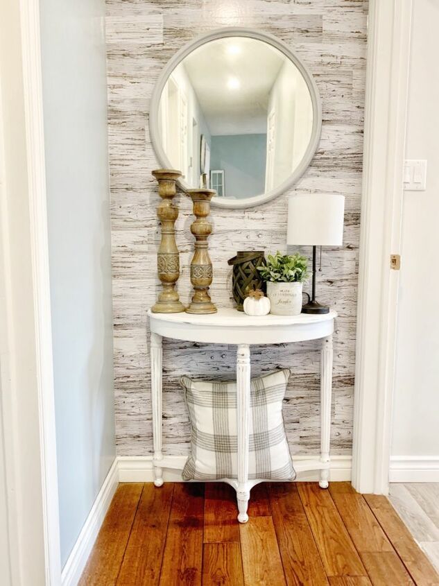 a white table with a mirror on top of it next to a lamp and vase