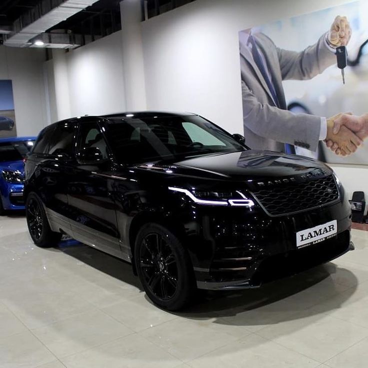 a black range rover parked in front of a large poster