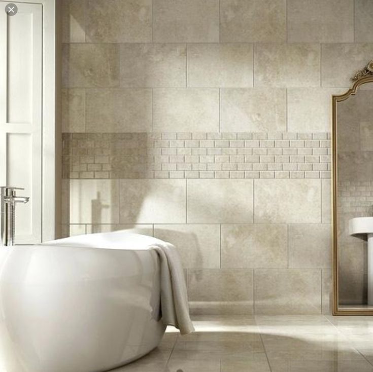 a white bath tub sitting next to a bathroom sink under a large mirror on the wall