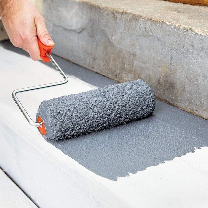 a person using a paint roller to paint concrete