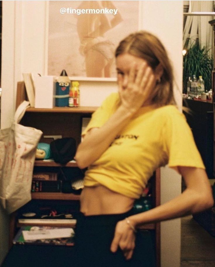 a woman standing in front of a book shelf holding her hands to her face