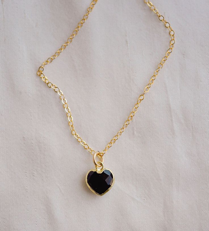 "Crafted onto a 14k gold filled chain and set in 24k gold electroplate, this black onyx heart is as precious as the affection it symbolizes. Make it that perfect gift for someone special, including yourself! Exuding protective and calming energies, Black Onyx is associated with the root chakra. It's believed to be an \"anti-panic\" stone which soothes stress and helps clear mental confusion and hyperactivity. GEMSTONE: Black Onyx STONE SIZE: average 10mm (.39\")  STONE SHAPE: Faceted Heart (Hear Black Heart-shaped Jewelry For Anniversary, Black Necklaces For Anniversary On Valentine's Day, Black Necklace For Anniversary On Valentine's Day, Valentine's Day Black Necklace For Anniversary, Black Necklaces With Birthstone For Anniversary, Black Enamel Necklace For Anniversary, Black Birthstone Necklaces For Anniversary, Black Birthstone Necklace For Gift, Black Birthstone Necklace For Gifts