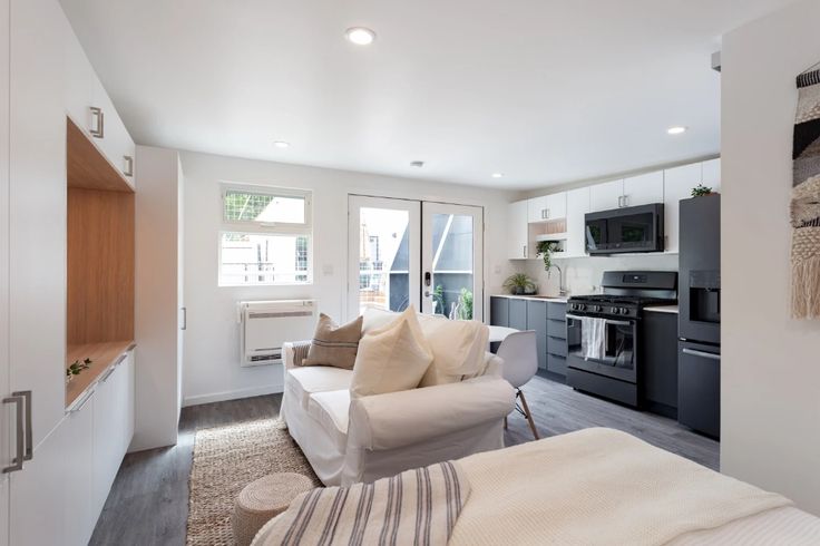 a living room filled with furniture and a kitchen in the backround behind it