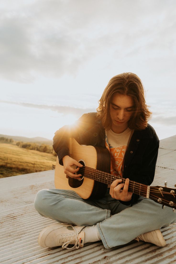 a man sitting on the ground playing an acoustic guitar