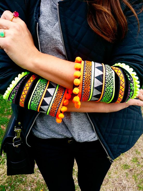 a woman is wearing colorful bracelets and holding a cell phone in her right hand