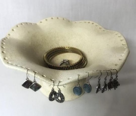 a ring holder with several rings and earrings hanging from it's side on a white wall