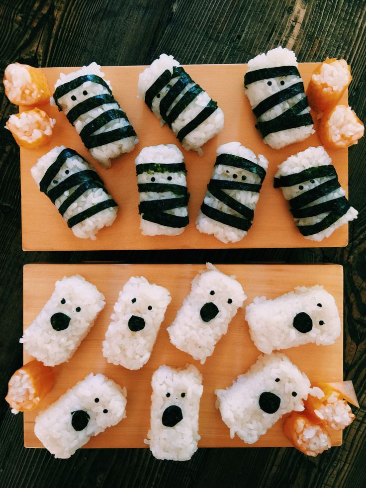 two cutting boards topped with sushi covered in black and white stripes, each being cut into smaller polar bears