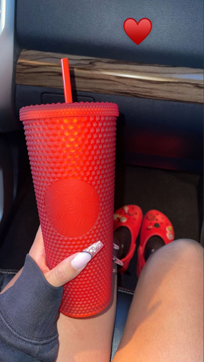 a woman holding a red cup with a straw in it