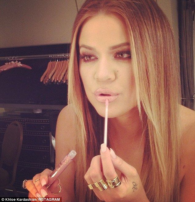 a woman is brushing her teeth in front of a mirror while holding a pink toothbrush