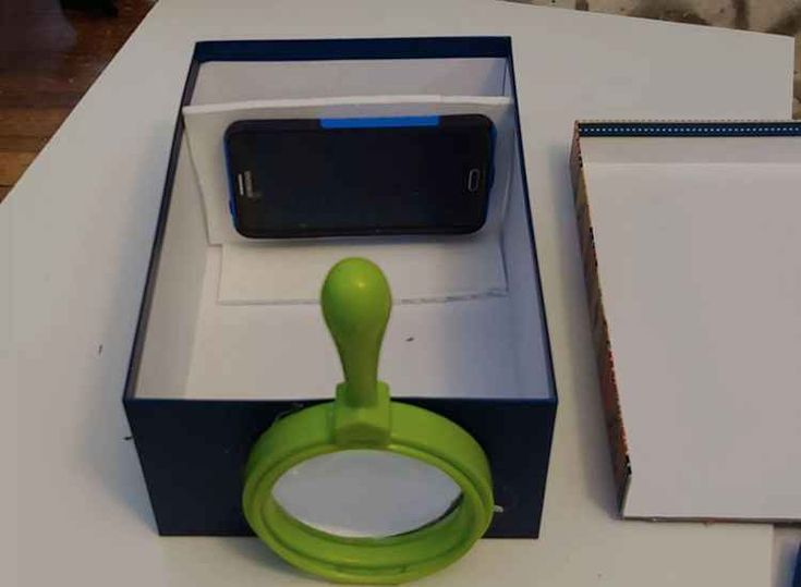 an open box with a cell phone in it sitting on a table next to a pair of scissors