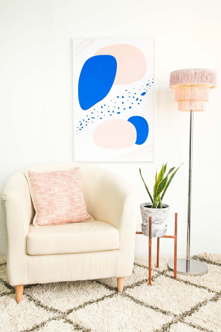 a white chair sitting next to a lamp on top of a rug in a living room