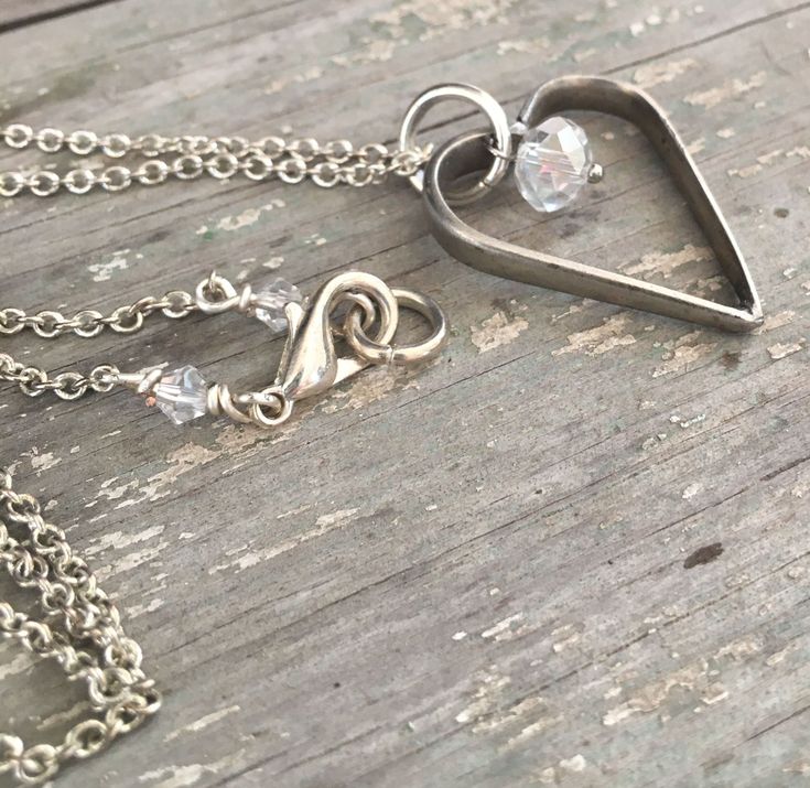 This unique silverware jewelry creation is a fork tine heart necklace. This sweet upcycled jewelry open heart necklace that is made from two left over fork tines from other upcycling projects. After being married together, as a heart, the pendant is then adorned with a clear faceted Czech glass bead. The whole silverware pendant hangs from a silverplate chain which itself is adorned with clear glass beads near the clasp. A unique feature about this particular necklace is that the heart hangs fro Hand Forged Silver Heart Necklace, Silver Hand Forged Heart Necklace, Silver Heart Necklace, Hand Forged, Open Heart Necklace, Silverware Jewelry, Upcycle Projects, Upcycled Jewelry, Antique Items, Jewelry Creation