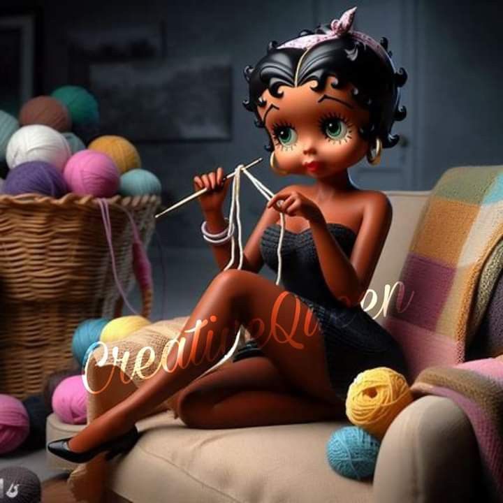 a doll is sitting on a couch next to some balls of yarn and knitting needles