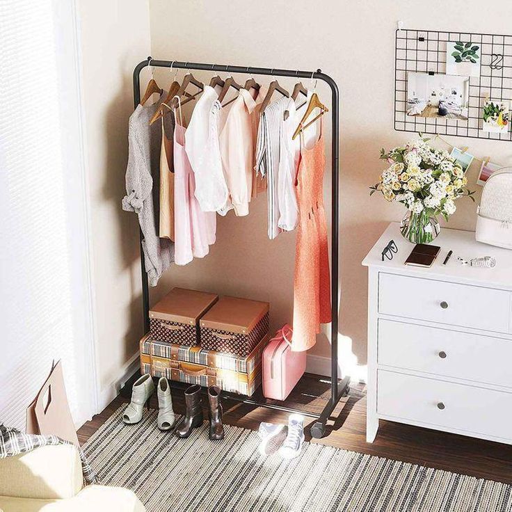 a rack with clothes hanging on it next to a dresser